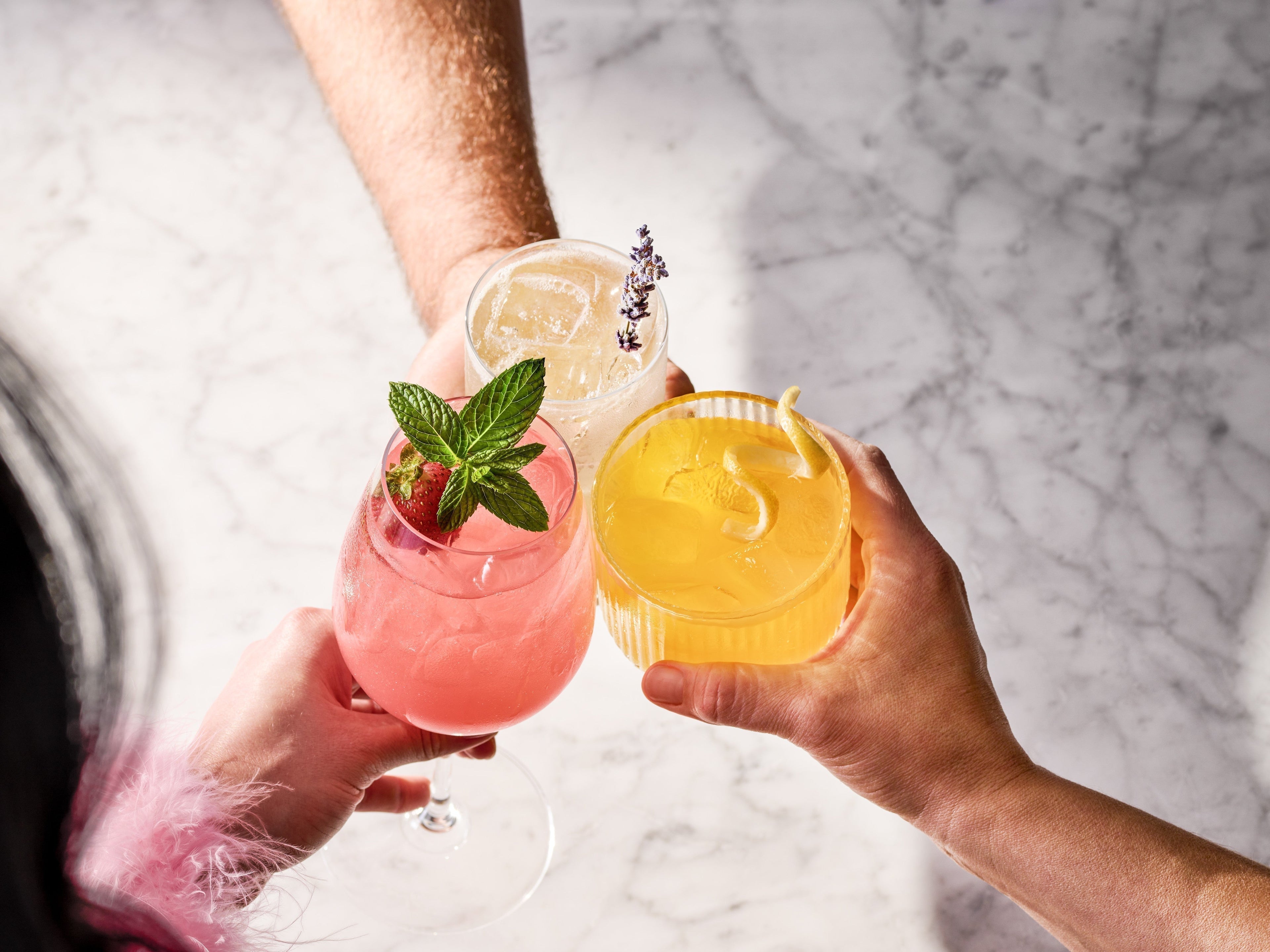 3 drinks being held together in a "cheers" motion in the center of the image
