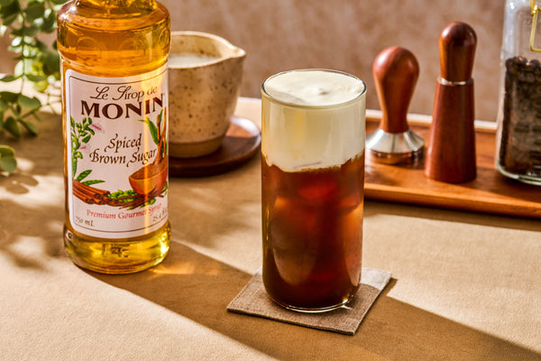 Iced cold brew topped with spiced brown sugar cold foam, made with Monin Spiced Brown Sugar Syrup.