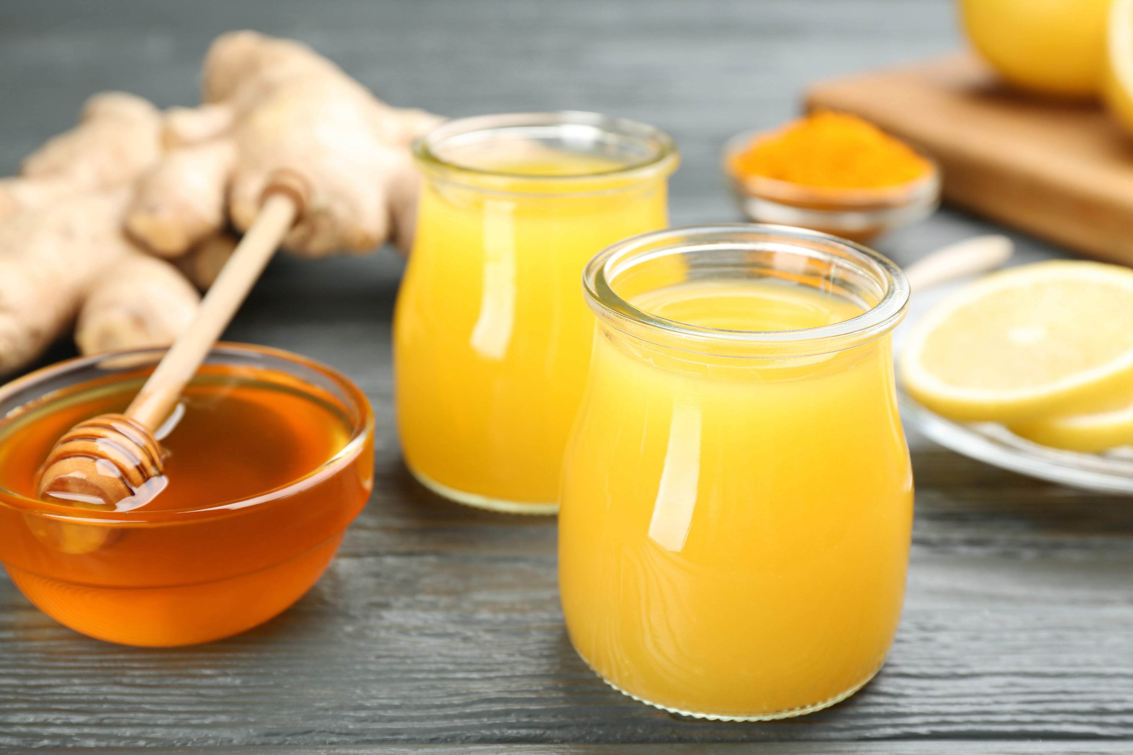 Immunity boosting drink and ingredients on grey wooden table, closeup