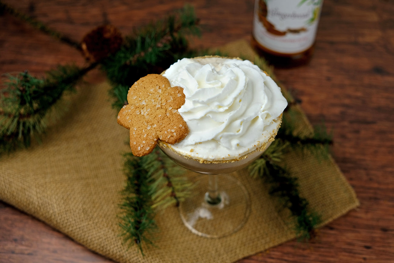 Gingerbread martini with whipped cream and a gingerbread cookie on top.