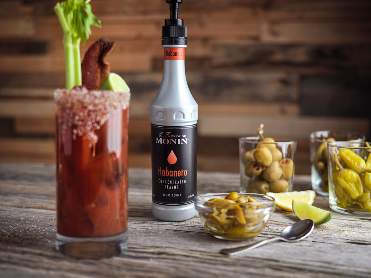 Bloody Mary with garnished next to a Monin Habanero Concentrated Flavor bottle.