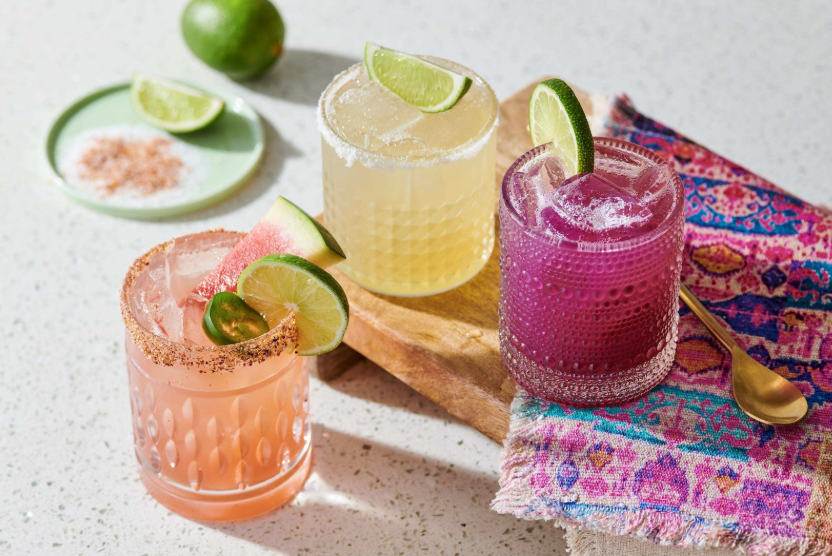 Three colorful Mexican-inspired drinks garnished with lime, jalapeño and watermelon