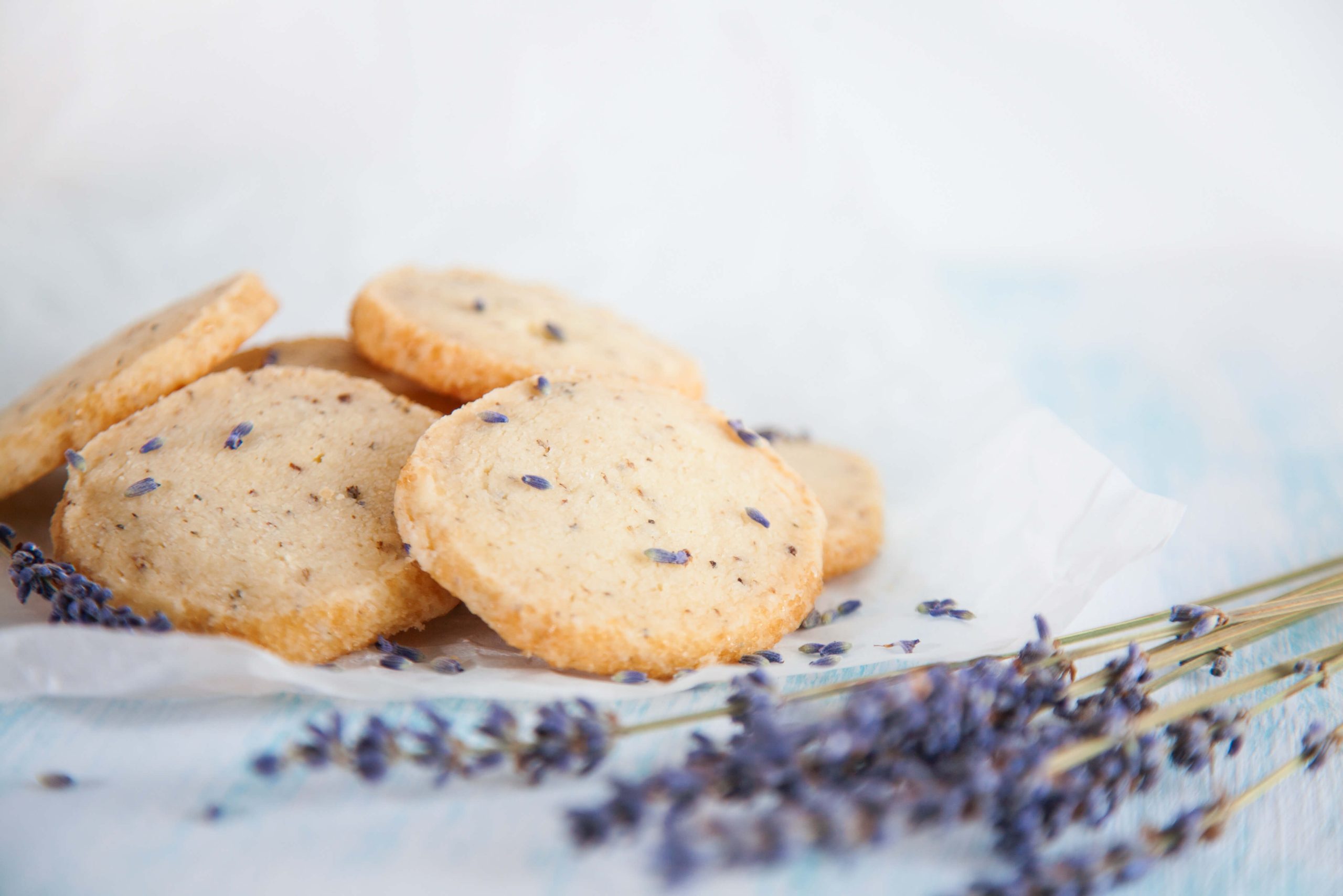 lavender shortbread cookies displayed on a cloth, with lavender sprigs lying in the foreground