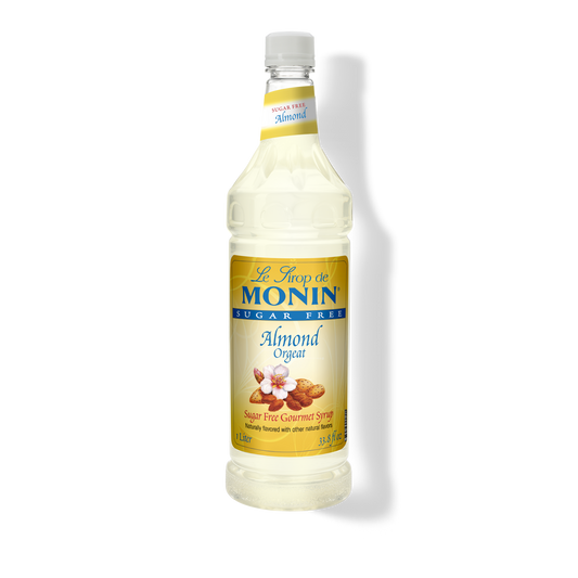 A bottle of Monin Sugar Free Almond Orgain syrup, featuring a white cap and a yellow label with blue branding, set against a plain white background with a soft shadow.