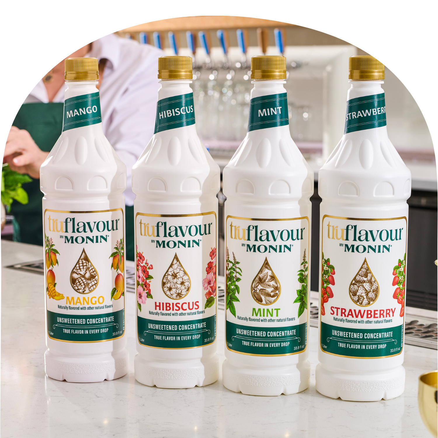 Four bottles of Monin syrup with different flavors on a kitchen counter.