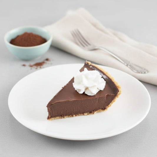 A slice of cherry chocolate pie made with Monin Black Cherry Puree, with a whipped cream dollop on top and served on a white plate.