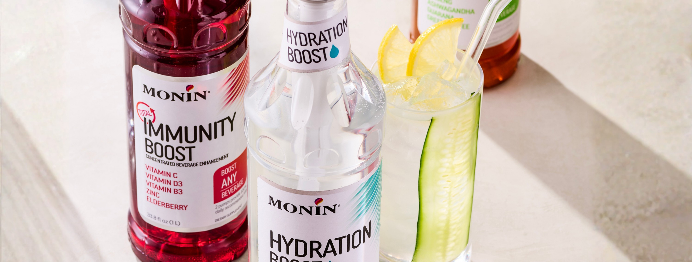 Monin immunity boost and hydration boost bottles with a cocktail in the background