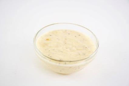 Glass bowl of creamy sauce on a white background