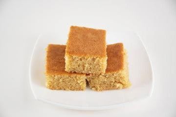 Three pieces of Brown Butter Toffee Blondie stacked on a white plate with a white background