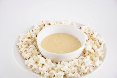 Popcorn surrounding a bowl of popcorn fondue on a white background