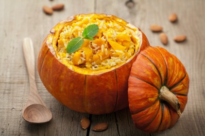 Stuffed pumpkin on a wooden surface with a wooden spoon