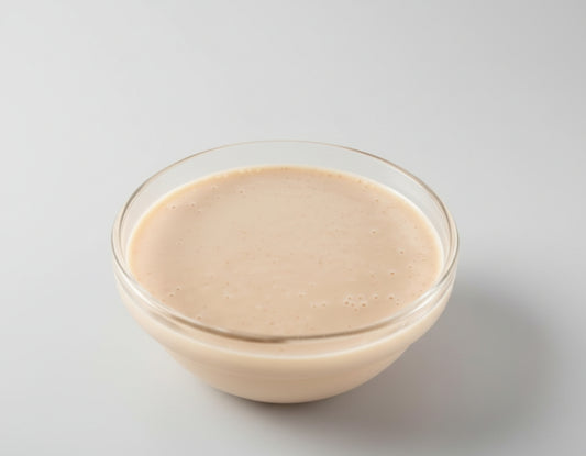 Glass bowl of creamy sauce on a white background