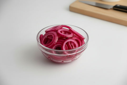 Glass bowl with pink pickled onions on a white background