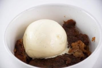 chai pudding served in a white bowl with a scoop of ice cream on top