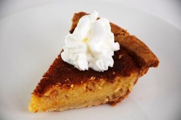 Slice of pumpkin pie with whipped cream on a white plate