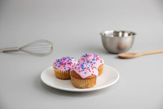 Cupcakes with pink icing on top decorated with rainbow sprinkles in a white background