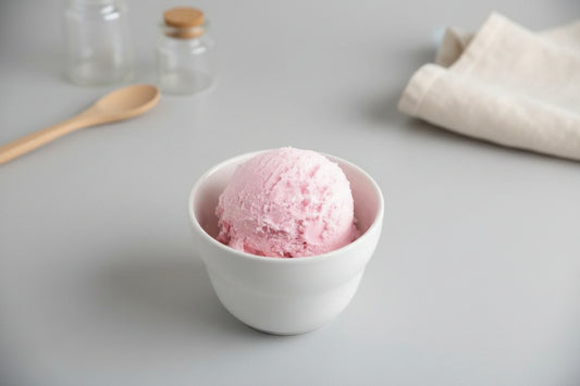 Pink ice cream in a white bowl on a light background