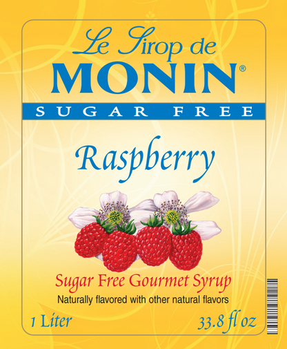 Front of a Le Sirop de MONIN Sugar Free Raspberry syrup box, with a yellow label showing raspberry berries, white flowers, and text including 'Raspberry', 'Sugar Free Gourmet Syrup', and '1 Liter / 33.8 fl oz'.