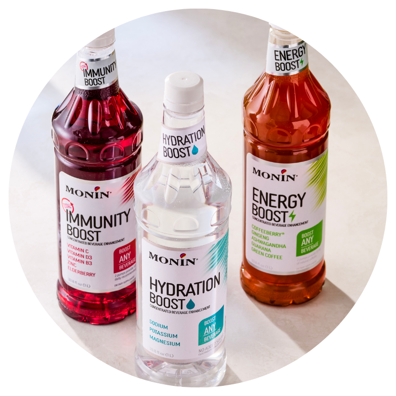 Three Monin beverage enhancement syrups—Immunity Boost, Hydration Boost, and Energy Boost—displayed on a light surface.